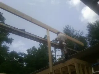 Carpenter setting a ridge beam over a new addition frame — Ice Dam Removal by Roofing Brothers in Woodside