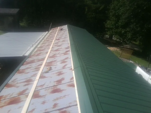 Old rusted panels beside newly installed green metal roofing — Wind Damage Roof Repair by Roofing Brothers in Woodside