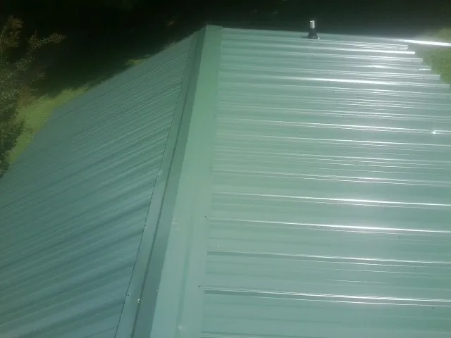 New green metal panels meeting at the ridge of a roof — Flat Roof Repair work by our crew in Woodside