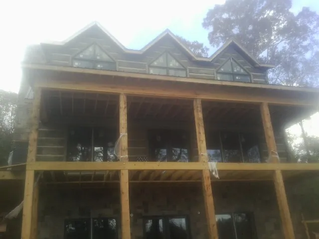 Dormers and porch framing on a large log home under construction — Roof Coating work by our crew in Woodside