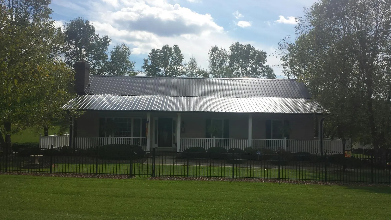 Gray metal roof on a brick ranch with a full width front porch — Gutter Guard Installation work by our crew in Woodside