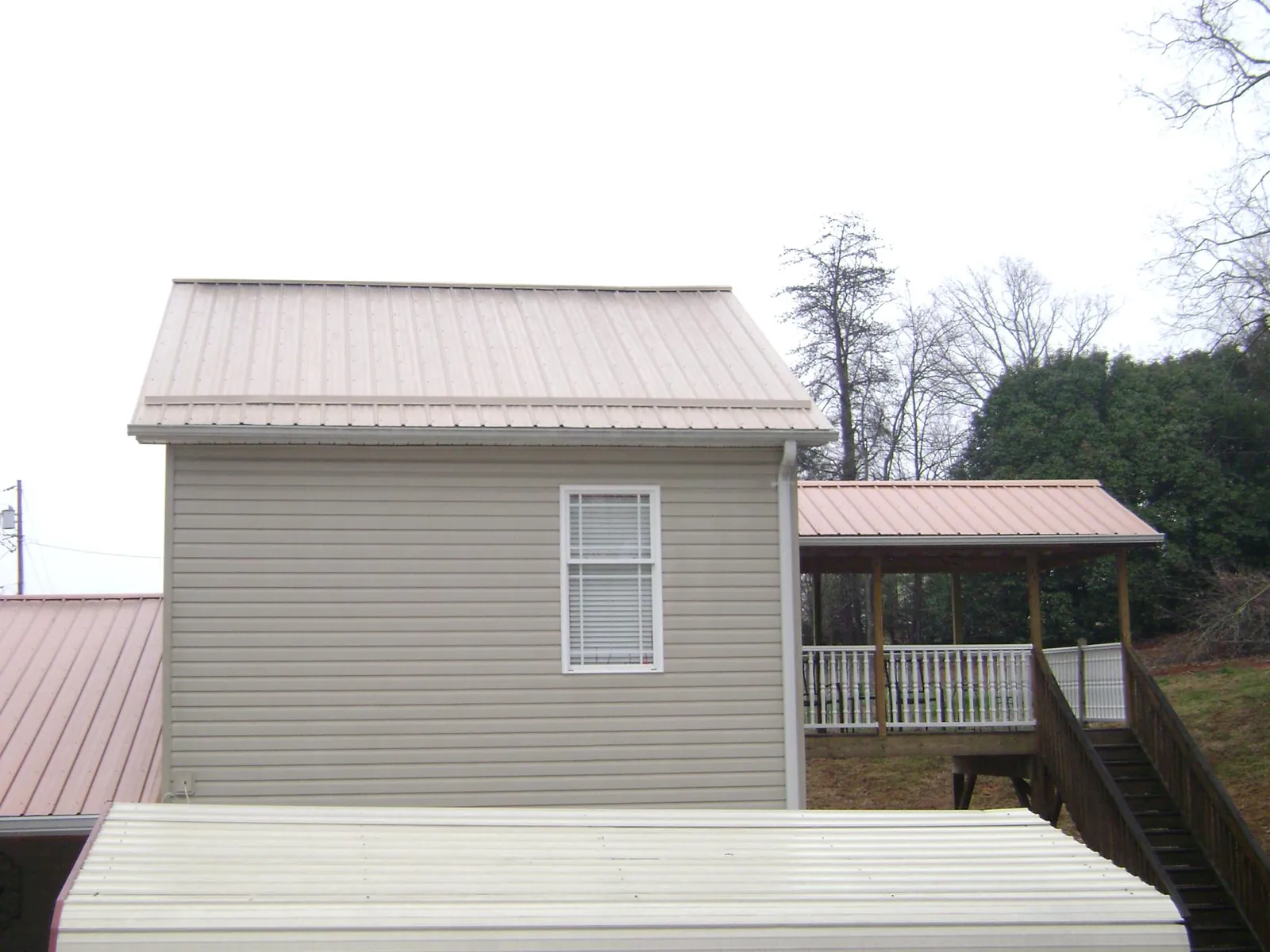 Tan metal roofs on a two story addition and attached porch, from a Roof Replacement job in Woodside